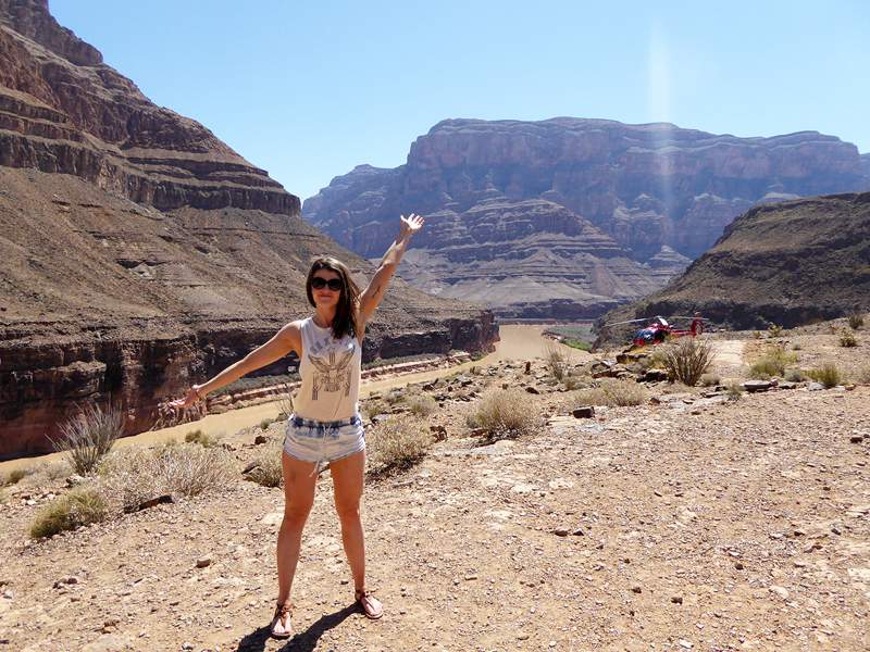 a woman wearing shorts and a tank top standing with arms raised above her head in front of the grand canyon. recover from an eating disorder