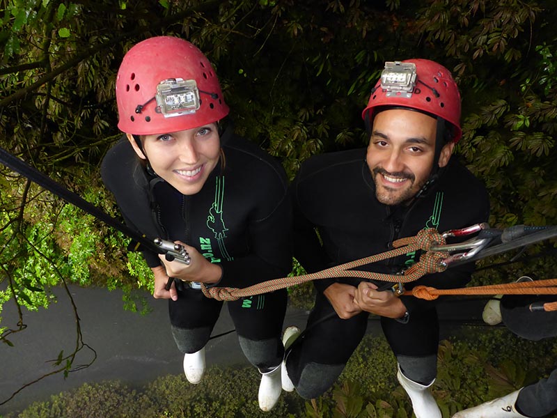 abseiling along a cave wall into glow worm caves