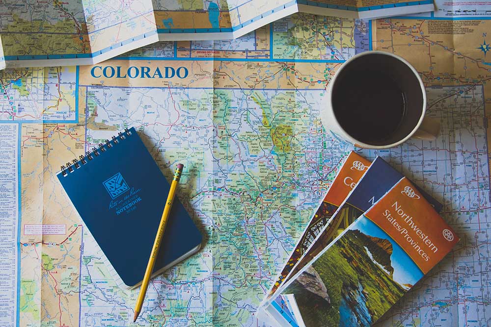 map of colorado with notepad, pencil, cup and AAA maps